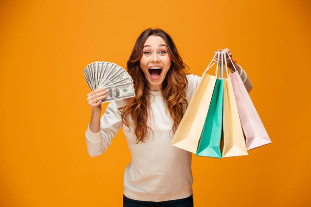 Excited screaming young lady holding shopping bags and money. - Photo, Image