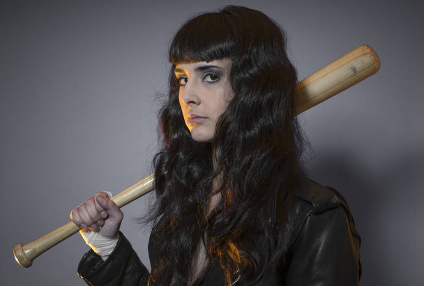 adolescence and delinquency, brunette woman in leather jacket and baseball bat with challenging aptitude - Фото, изображение