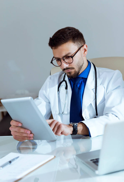 Confident male doctor working with his digital tablet in the office. - Foto, immagini