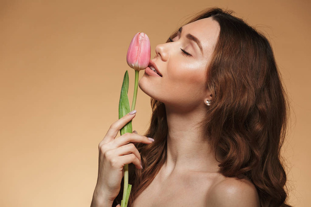 Gentle beautiful young woman holding one tulip flower. - 写真・画像