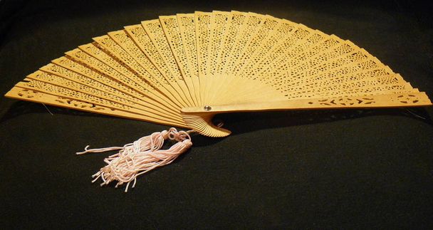 Antique wooden hand fan, wooden fan, openwork fan, wood carving, openwork pattern, beige, close-up, black background. Headstock stock image. - Photo, Image