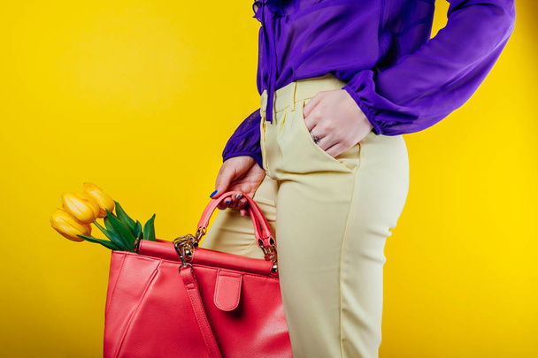 Foto de estudio de una mujer con traje de primavera y sosteniendo una bolsa con tulipanes amarillos
 - Foto, Imagen