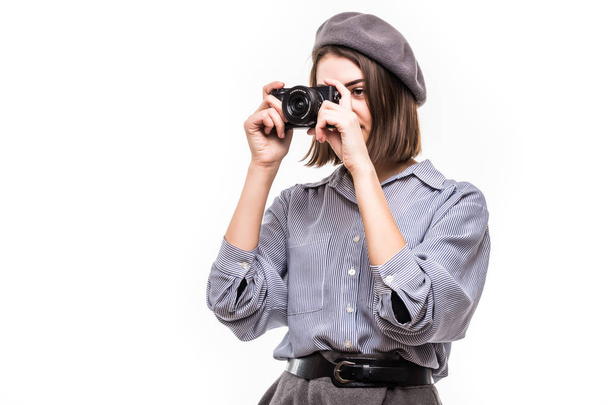 Portrait of an excited woman wearing beret holding photo camera over white background - Photo, Image