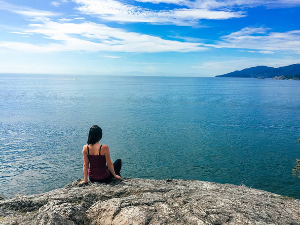 Женщина на скале с видом на океан
 - Фото, изображение