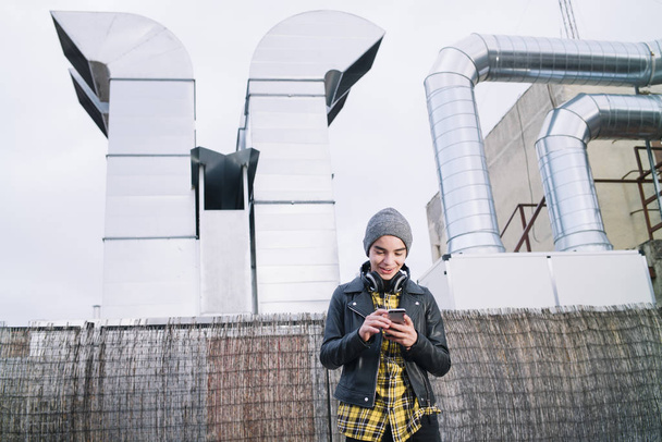 молодий хлопчик з смартфоном і навушниками на вулиці
 - Фото, зображення