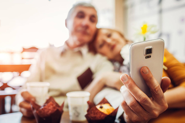 Casal sênior faz uma selfie usando um telefone no café. Celebração do aniversário
. - Foto, Imagem