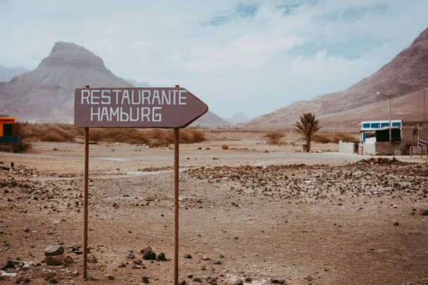 Old signpost in abandoned barren desert scenery. Volcano rugged on the horizon. Sao Vicente Cape Verde - Foto, immagini
