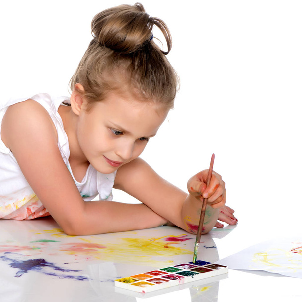 A little girl paints with paint and brush. - Foto, Imagen