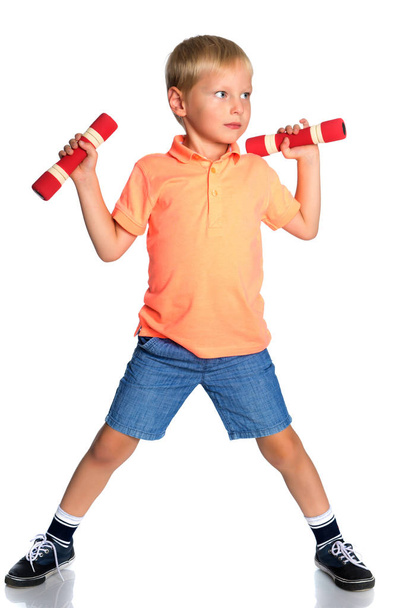 A little boy is lifting dumbbells. - Фото, изображение