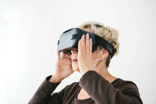 Una anciana con gafas de realidad virtual. Una persona mayor usando tecnología moderna
. - Foto, Imagen