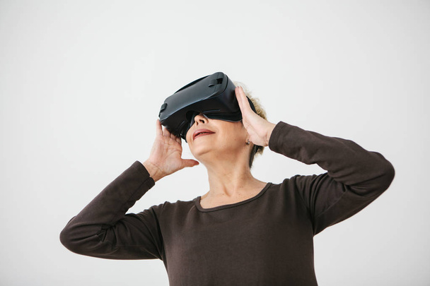 An elderly woman in virtual reality glasses. An elderly person using modern technology. - Photo, Image