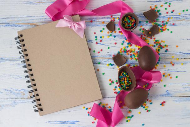 Πασχαλινά σοκολατένια αβγά, ροζ ταινία και το σημειωματάριο Πάσχα Multicolore - Φωτογραφία, εικόνα