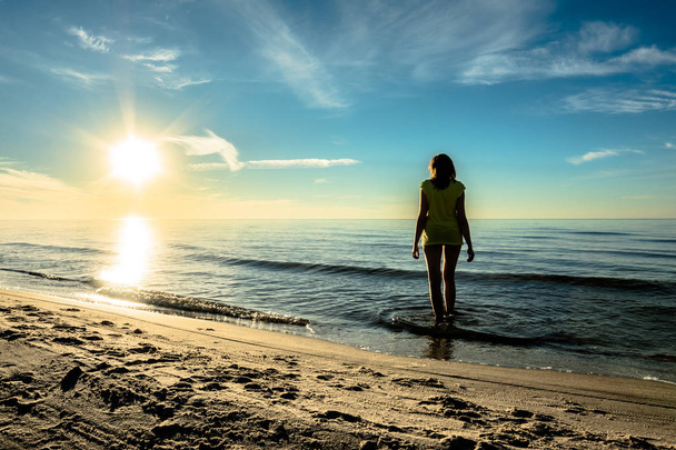 Attractive woman in sunset sea, girl on the beach in water, coast illuminated with sun rays in the summer, Baltic Poland - Photo, image