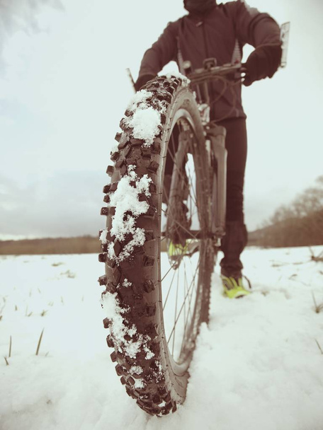 Hombre con bicicleta de montaña en la nieve. Camino perdido en la deriva de nieve. Detalle rueda delantera
. - Foto, imagen