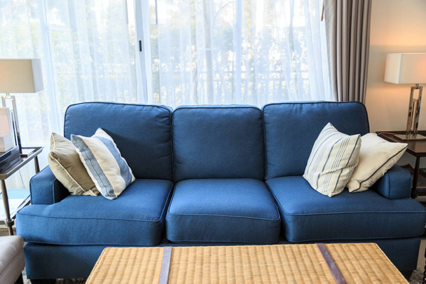 Un oreiller sur un canapé bleu avec lampe dans le salon
 - Photo, image