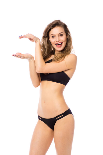 Studio shot of a young woman in a bikini isolated on white showing size sign with big smile - Photo, Image