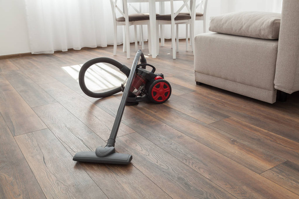 Vacuum cleaner on the wooden floor. Cleaning home - Photo, Image