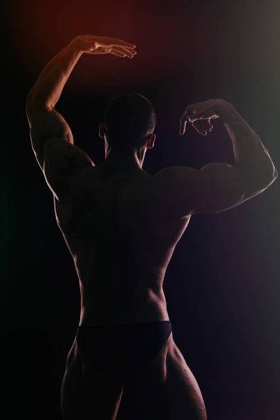 Мускулистый человек бодибилдер тренировки в тренажерном зале и позирования мышц
 - Фото, изображение