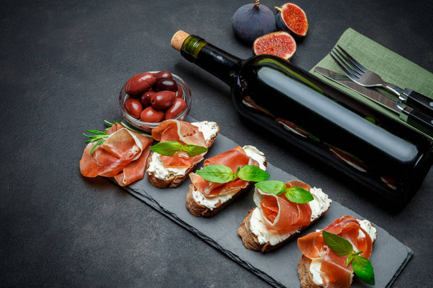 italian food with olives, wine and prosciutto bruschettas on stone board - Foto, immagini