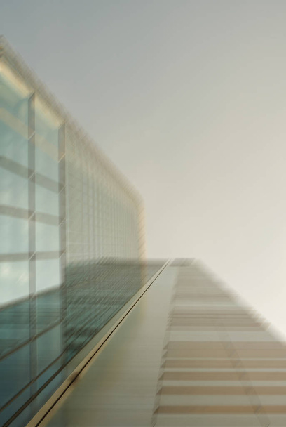 Дефокусоване зображення низького кута зовнішнього вигляду сучасного скляного хмарочоса на фоні неба в діловому районі міста
 - Фото, зображення