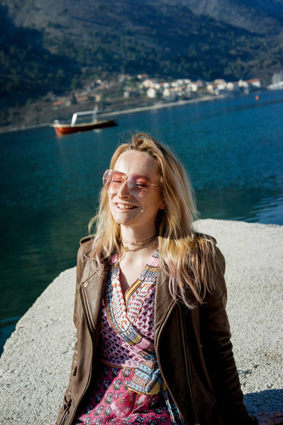 Young blond woman in pink glasses and dress near the sea on a su - Photo, Image