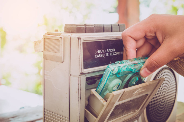 Estilo de vida retro - Mujer casete de cinta de mano con reproductor de cassette y grabadora para escuchar música - efecto de tono de color vintage
. - Foto, Imagen