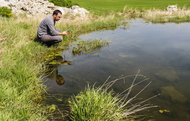 Cientista que mede a qualidade ambiental da água numa zona húmida
 - Foto, Imagem