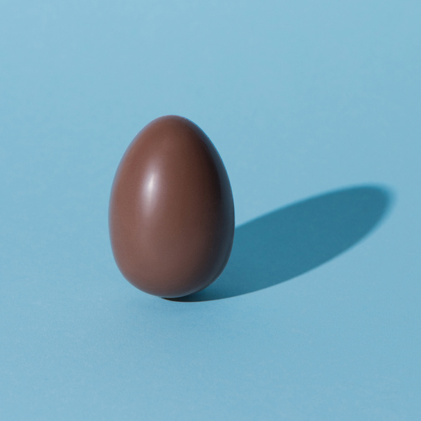 one chocolate easter egg on blue surface - Φωτογραφία, εικόνα