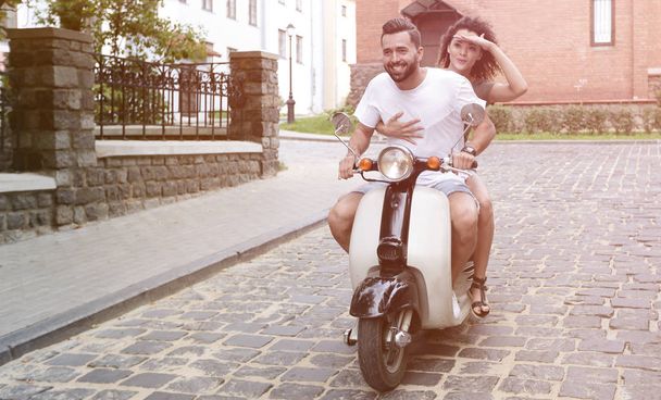Young couple riding motor scooter in city - Foto, Bild