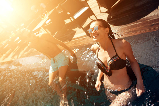 Jeune couple heureux se repose sous le soleil dans la piscine à l'heure d'été. Compagnie d'amis insouciants passer du temps à nager dans la piscine. - Photo, image
