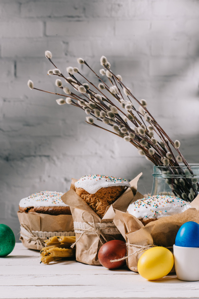 Пасхальный хлеб, покрашенные яйца, кексы и свечи на деревянном столе
 - Фото, изображение