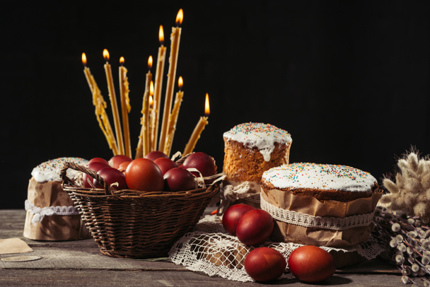 zoete zelfgemaakt gebak met Pasen, schilderde kippeneieren en brandende kaarsen op tafel - Foto, afbeelding