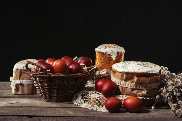 木製テーブルのバスケット、柳の小枝、イースターのおいしいケーキで塗られた卵のクローズ アップ ビュー - 写真・画像