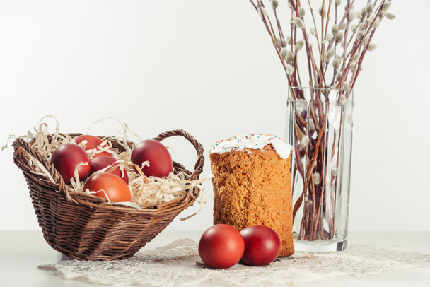 painted chicken eggs in basket, easter cake and catkins in vase on grey - Fotografie, Obrázek