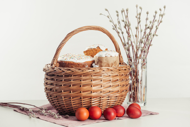 basket with easter cakes, painted eggs and catkins on grey  - Photo, Image