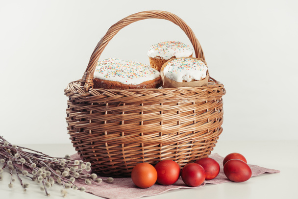 close-up view of basket with easter cakes, painted eggs and catkins on grey  - Fotoğraf, Görsel