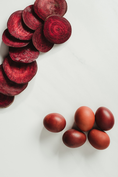 top view of painted easter eggs and beetroot slices on grey   - Foto, imagen