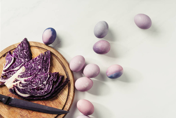 top view of violet painted eggs and purple cabbage with knife on wooden cutting board on grey - Photo, Image