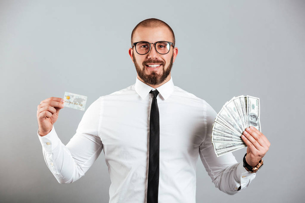Photo of rich man 30s in glasses and tie showing credit card and - Foto, immagini