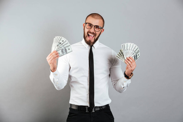 Portrait of a happy businessman holding lots of cash - Foto, imagen