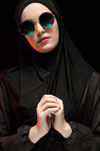 Güneş gözlüğü ve geleneksel giysiler içinde dua eden genç Müslüman kadın portresi - Fotoğraf, Görsel