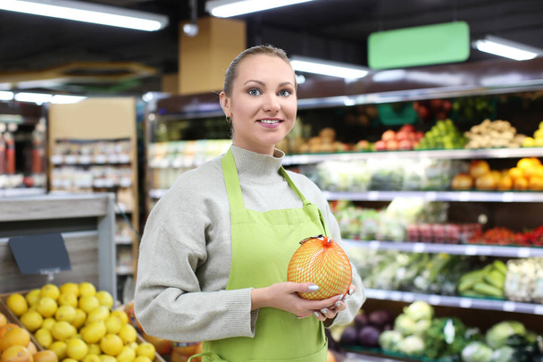 Portrait of young woman with citrus fruit in shop. Small business owner - Foto, Imagen