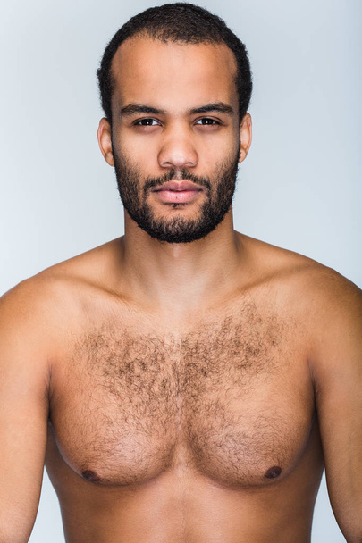 Handsome and confidant. Portrait of handsome shirtless young black man looking at camera while standing against white background - Фото, изображение