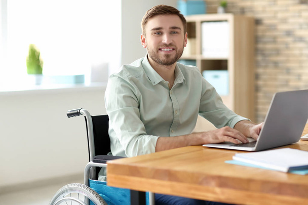 Young man in wheelchair at workplace - Fotoğraf, Görsel