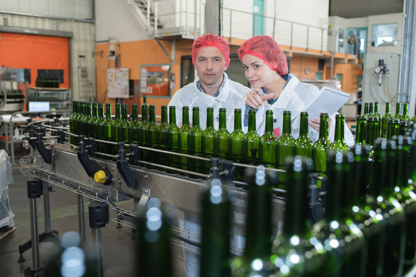 man and woman wearing uniform standing among a brewery - Foto, Bild