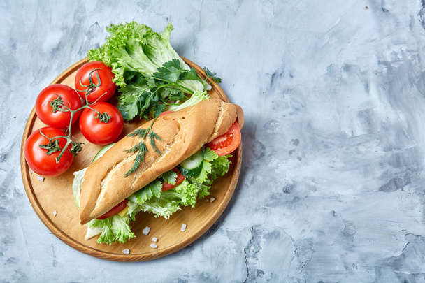Fresh sandwich with lettuce, tomatoes and cheese served on wooden plate over white textured background, selective focus - Φωτογραφία, εικόνα