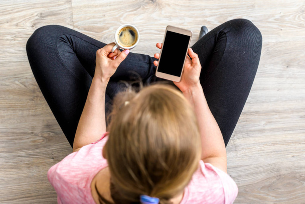 Woman using smartphone and coffee, top view, smart mobile phone used by hipster person at home - Photo, Image