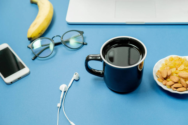 blauer Arbeitsplatz mit Laptop, Früchten und schwarzer Teetasse.  - Foto, Bild