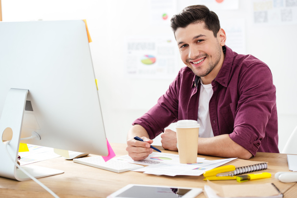 портрет улыбающегося бизнесмена на рабочем месте с бумагами и кофе, чтобы пойти в офис
 - Фото, изображение