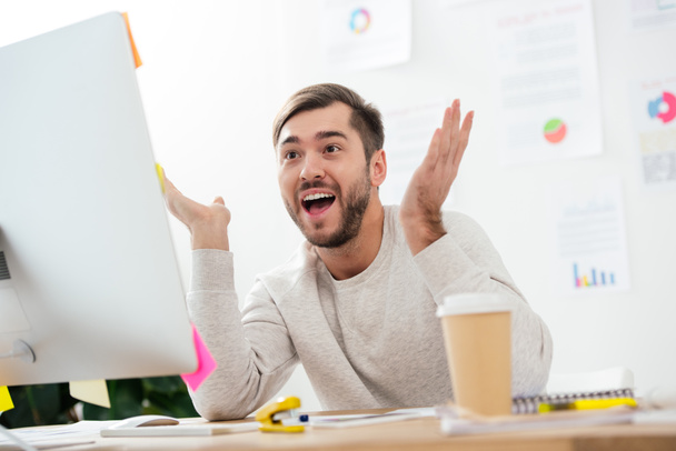 Portret van geschokt zakenman kijken naar computerscherm op werkplek op kantoor - Foto, afbeelding